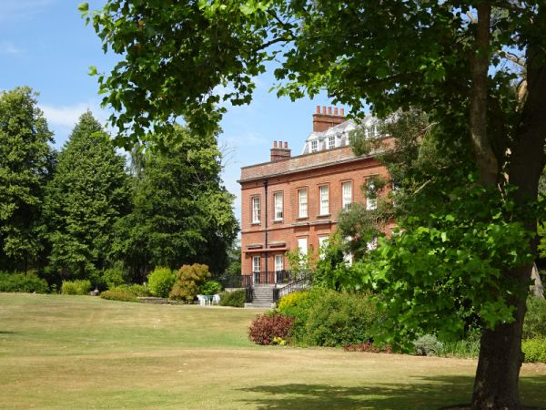 Redisham Hall set in trees with lawn in front.