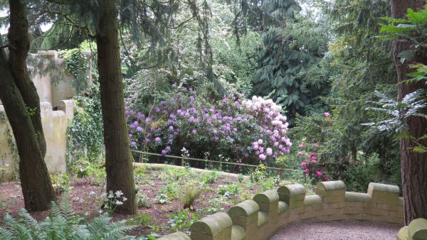 Stone castellated wall looking down hill with trees and shrubs