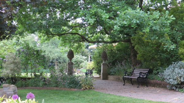 Wide footpath under trees with seat and two features on plinths.