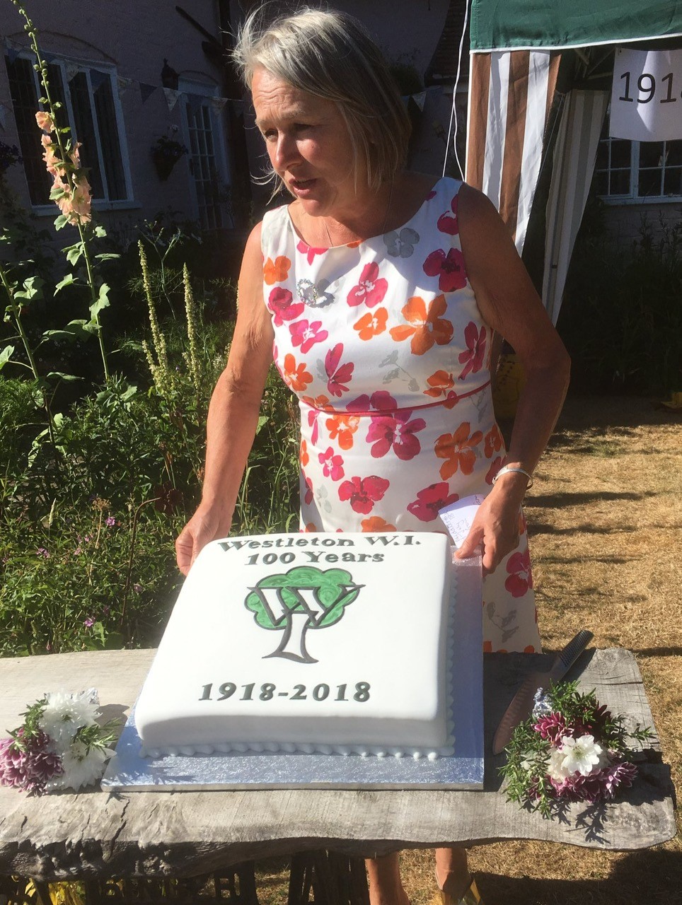 WI Branch President speaking behind centenary cake.