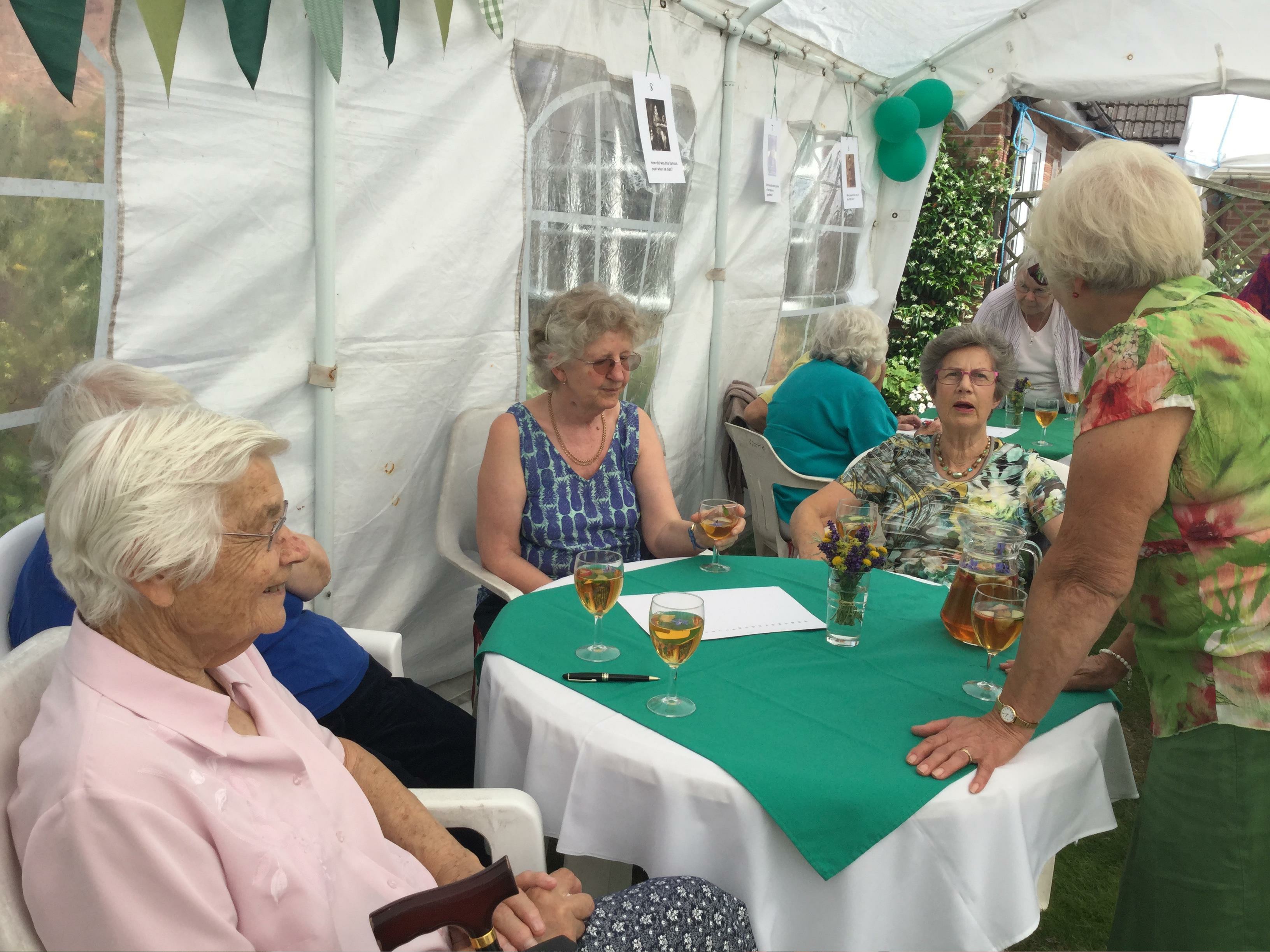 Pimms, Raffle and a Quiz in President Pat Swindell's garden. Members round a table.